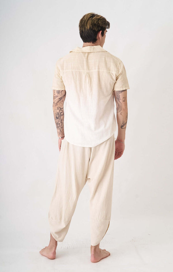 Arka görünümde minimalist pastel krem erkek gömlek ve hafif pantolon, şık rahatlık sunuyor.